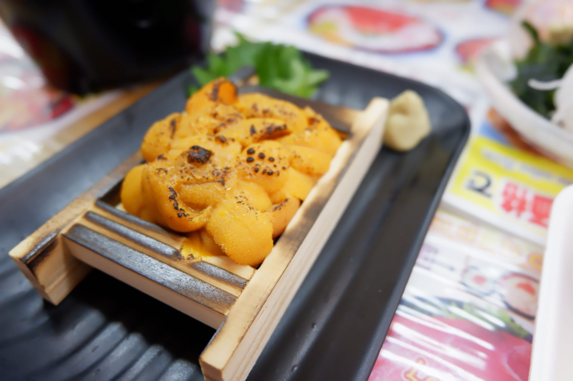 อูนิสดบนถาดไม้บนจานดำ ในทริปขับรถจากฮอกไกโดถึงโตเกียว