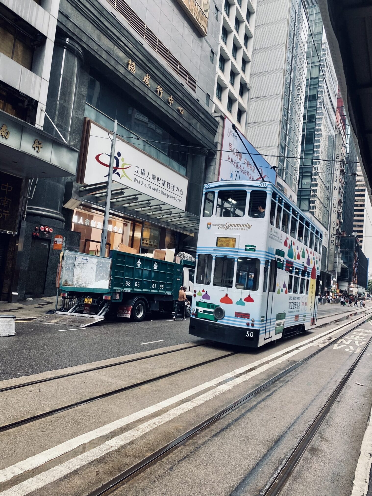 รถรางฮ่องกงสีขาววิ่งบนราง พร้อมป้ายโฆษณา "HKUSPACE Community College" ในฮ่องกง กิน เที่ยว ไหว้พระ ฮ่องกง