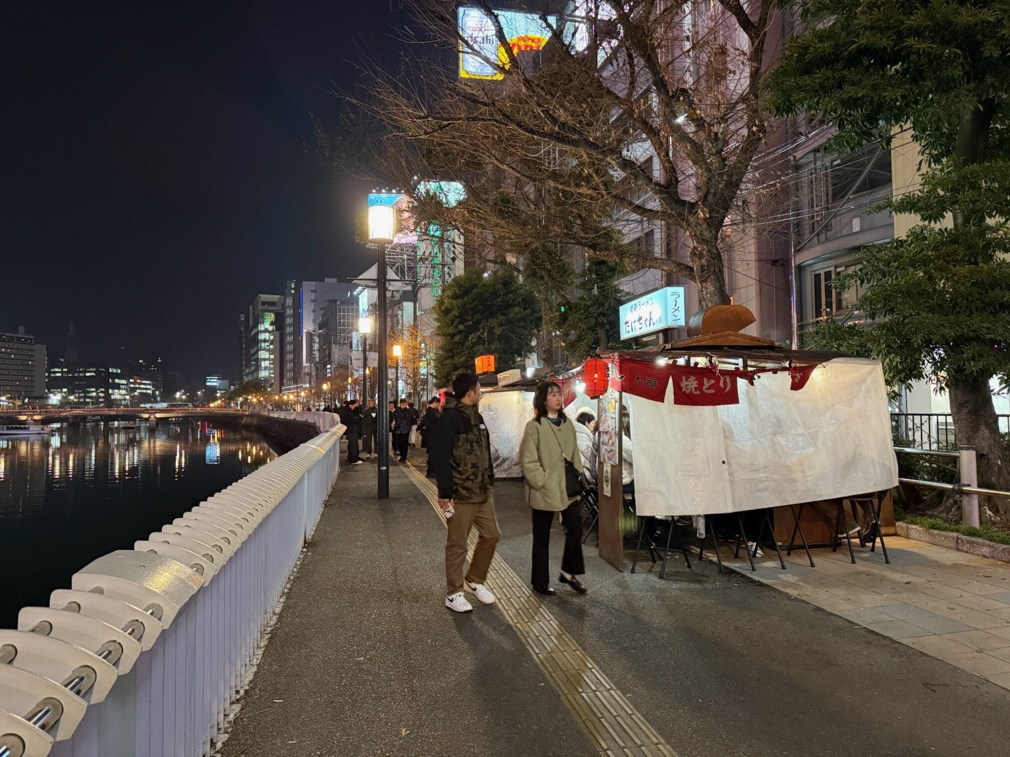 ริมน้ำฟุกุโอกะยามค่ำคืน มีร้านอาหารแผงลอยเรียงราย ขับรถเที่ยวคิวชู