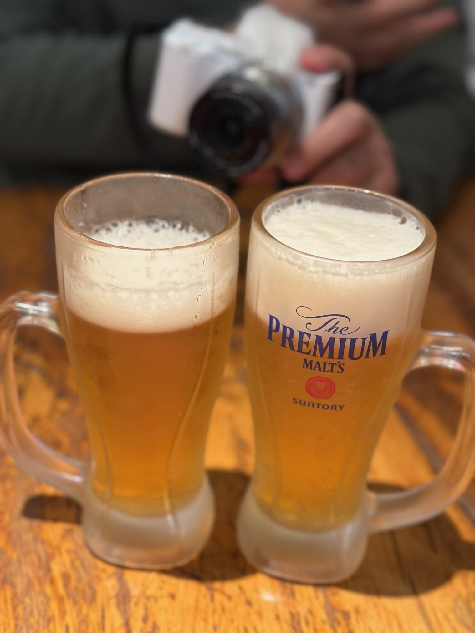 แก้วเบียร์ The Premium Malt's สองแก้วบนโต๊ะไม้ ขับรถเที่ยวคิวชู