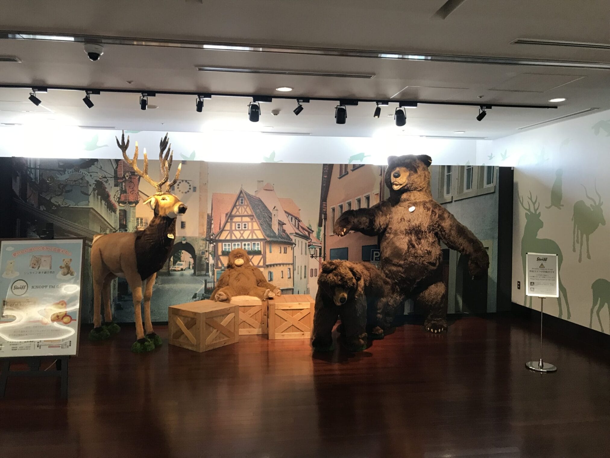 ตุ๊กตา Steiff ขนาดใหญ่จัดแสดง: กวาง, หมีนั่ง, และหมีสองตัวยืนอยู่หน้าฉากหลังเมืองเก่า