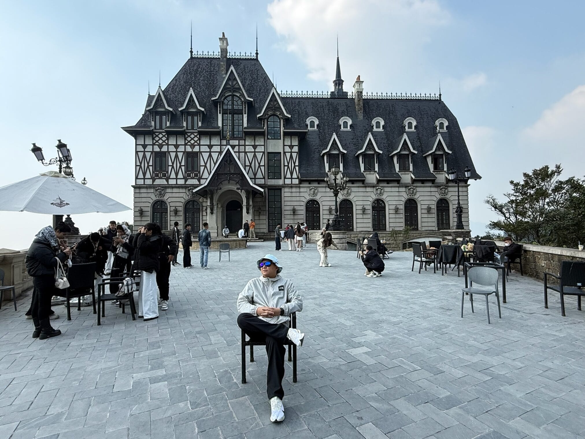 ชายหนุ่มนั่งบนเก้าอี้หน้าอาคารสไตล์ยุโรปในการเดินทาง "ฮานอย – ตามด๋าว EP1