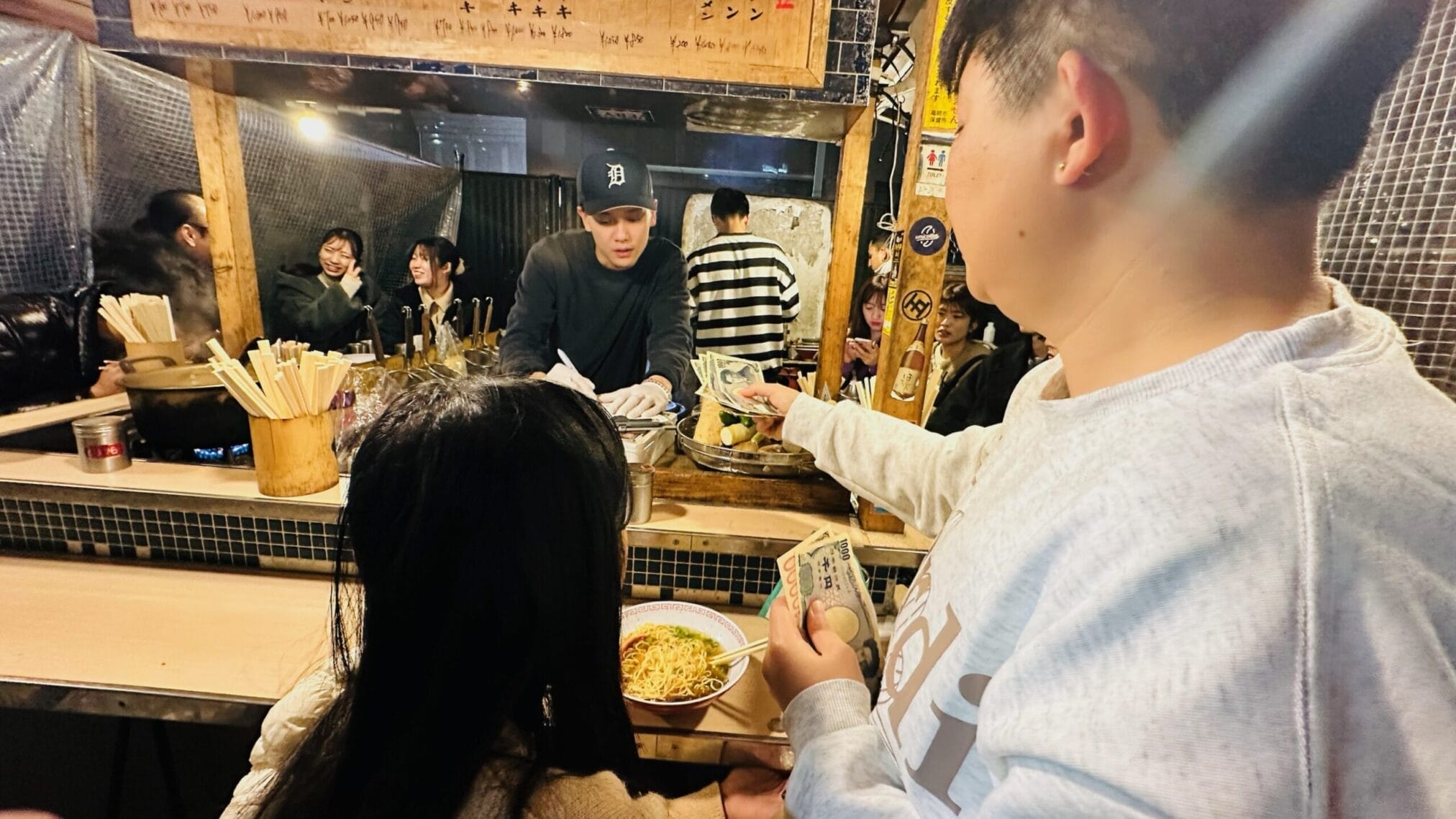 ลูกค้าจ่ายเงินซื้อราเม็งที่ร้านอาหารริมทางในฟุกุโอกะระหว่างทริปคิวชู