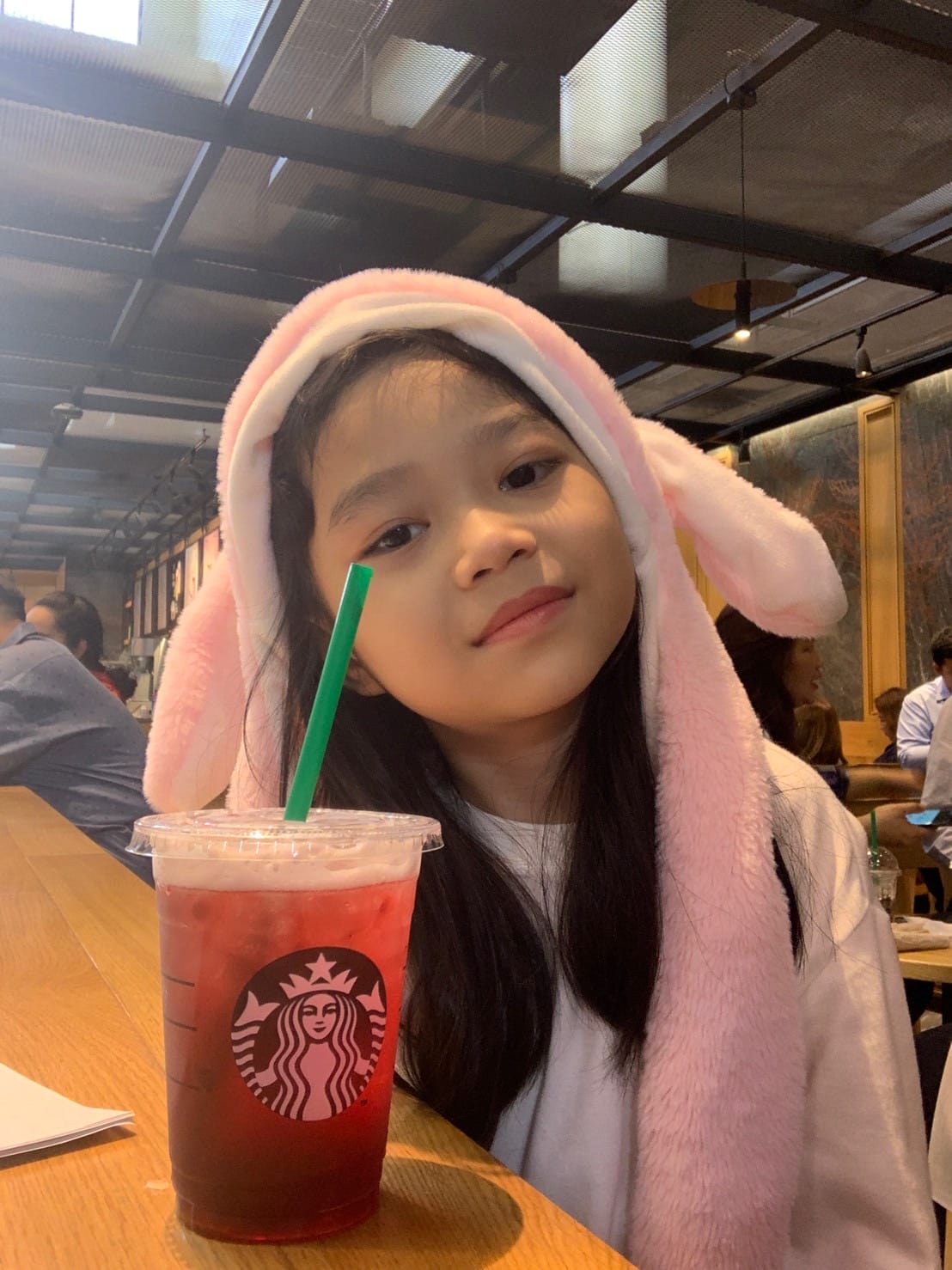 เด็กหญิงใส่หมวกกระต่ายสีชมพูกับเครื่องดื่มสตาร์บัคส์