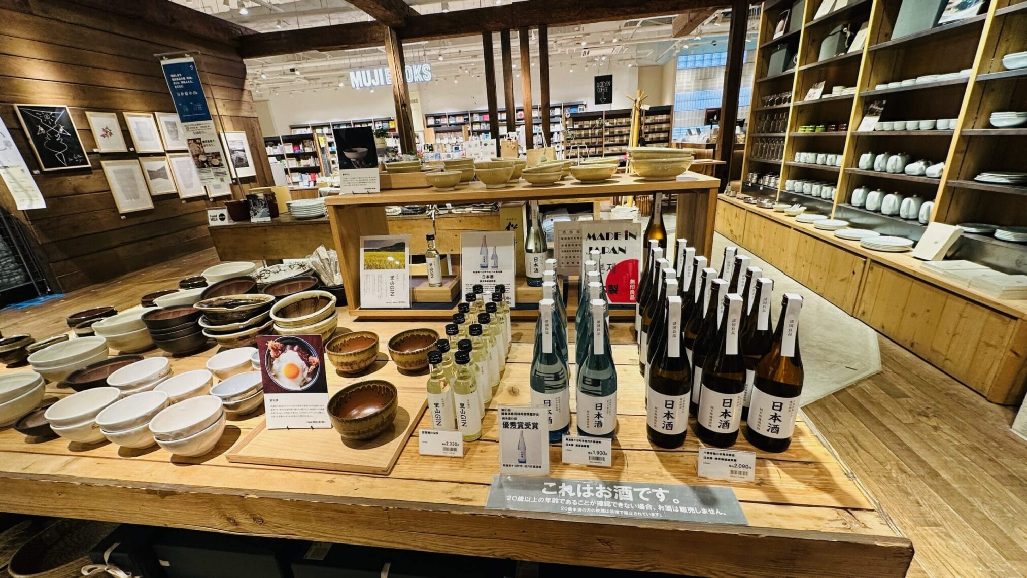 ชั้นวางสินค้าในร้าน MUJI มีเครื่องปั้นดินเผาและสาเกญี่ปุ่นหลากหลายชนิด