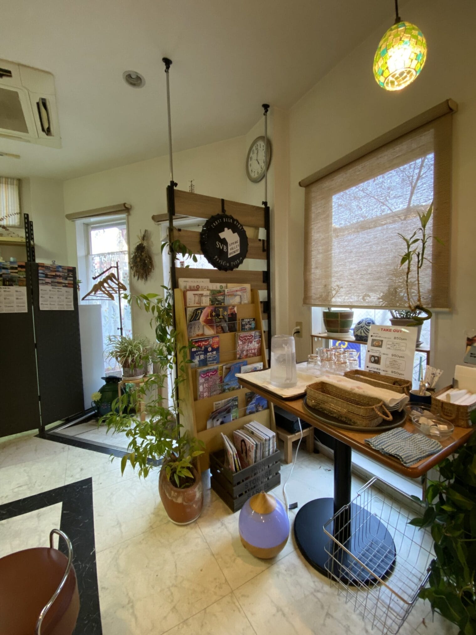 ภายในร้านกาแฟในฟุกุโอกะ มีชั้นวางหนังสือและป้าย "CRAFT BEER HERE!