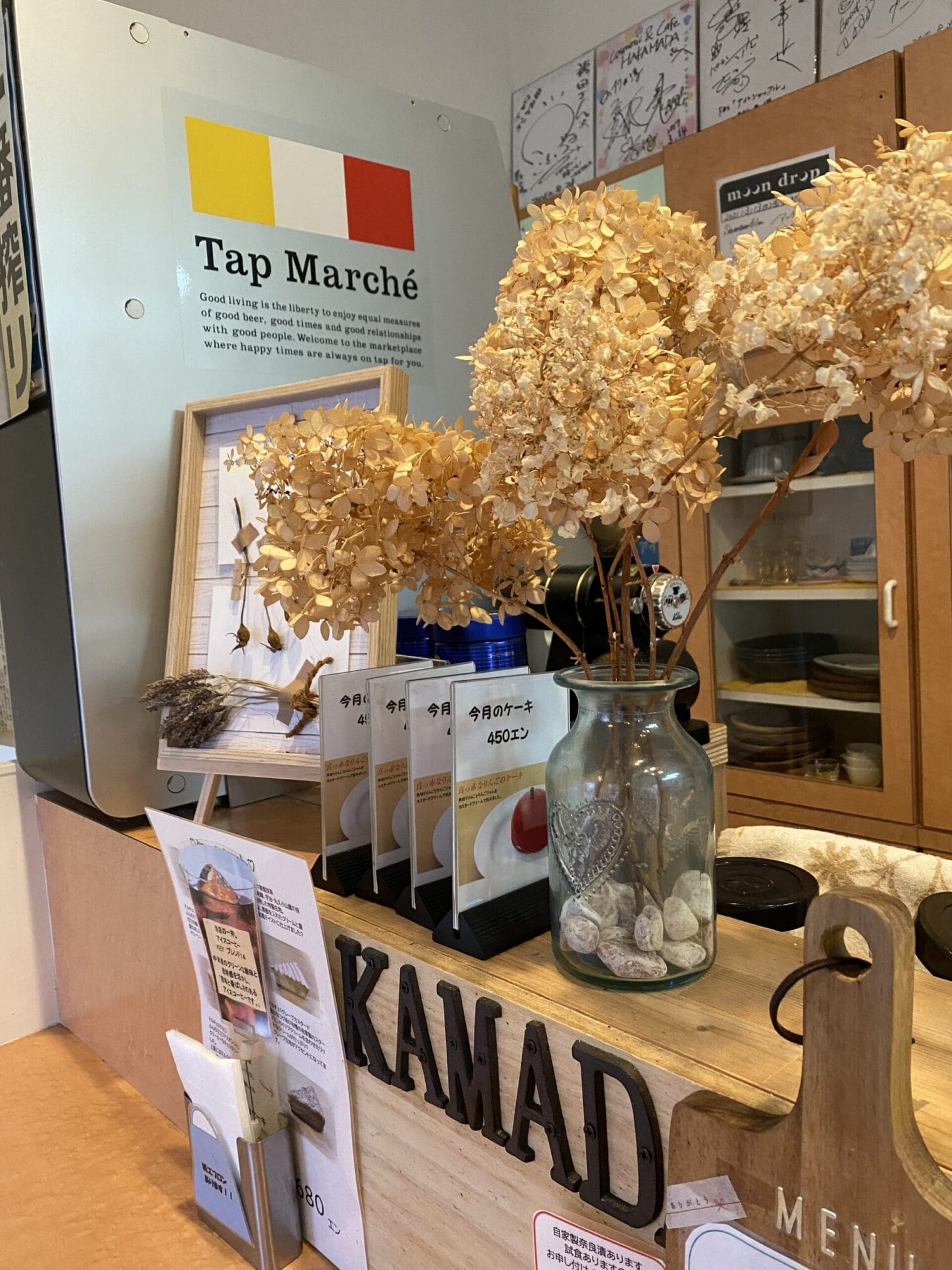 เคาน์เตอร์ร้านกาแฟ Kamad พร้อมเมนู Tap Marché และดอกไม้แห้งสวยงาม