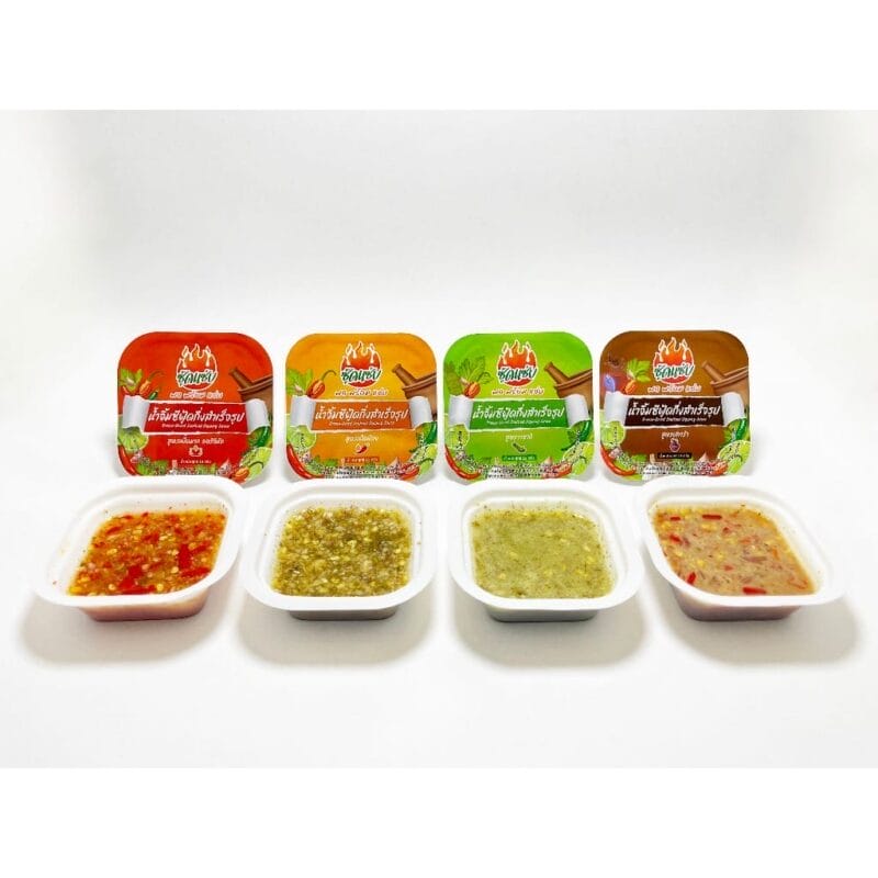 ซอสพริก 4 รสชาติในถ้วยพร้อมฝาปิดสีแดง ส้ม เขียว และน้ำตาล 4 chili sauce flavors in small containers with red, orange, green, and brown lids