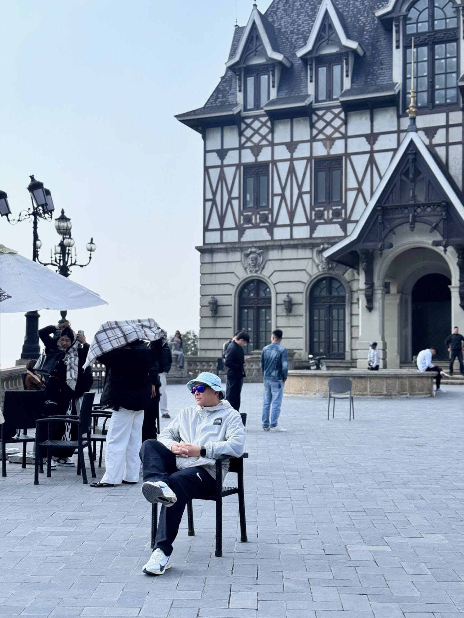 ชายสวมหมวกนั่งบนเก้าอี้ในฮานอย อาคารสไตล์ยุโรป