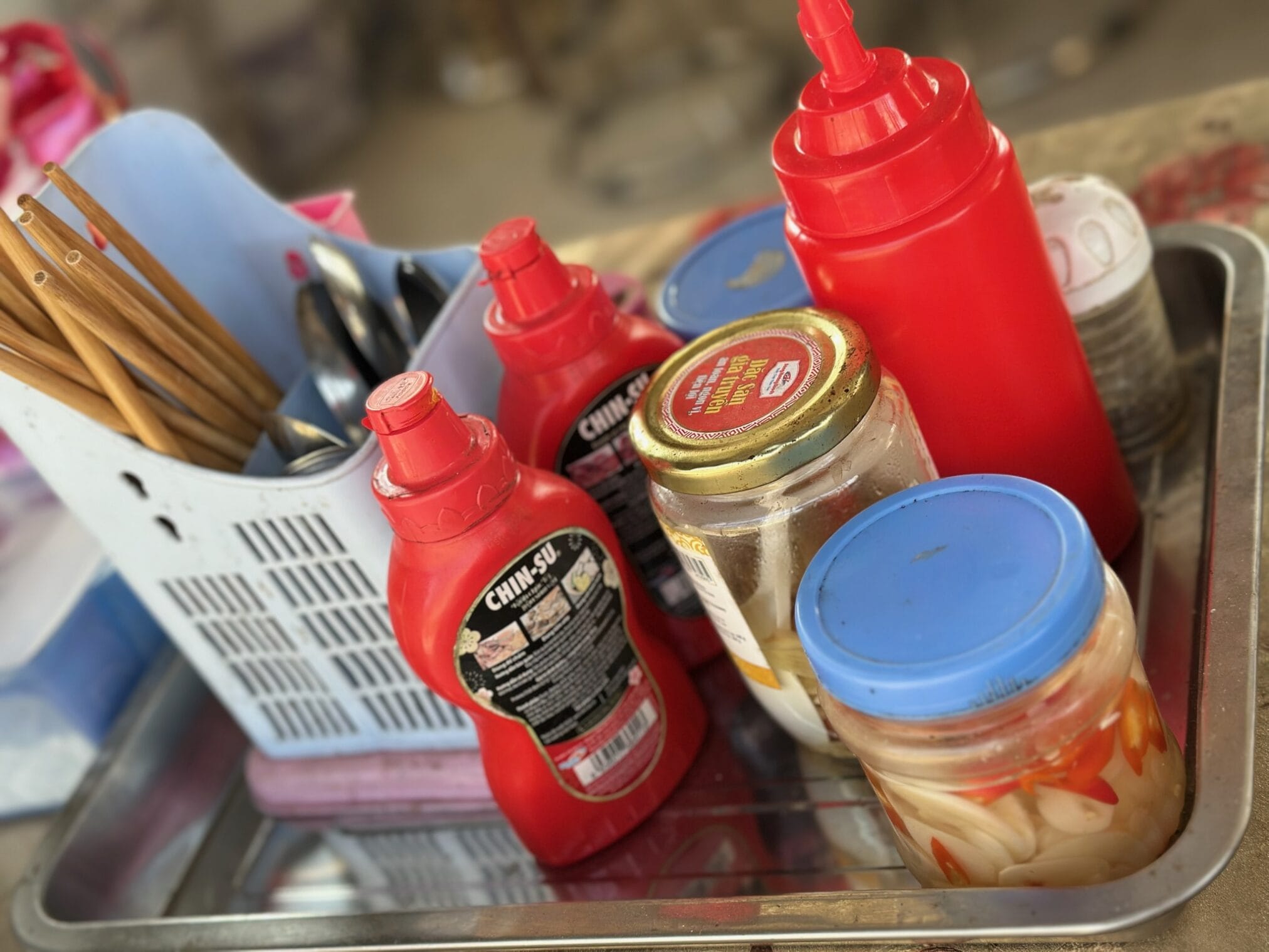 เครื่องปรุงรสเวียดนามบนถาด, มีซอสพริก, น้ำปลา, พริกน้ำส้ม, ตะเกียบและช้อน