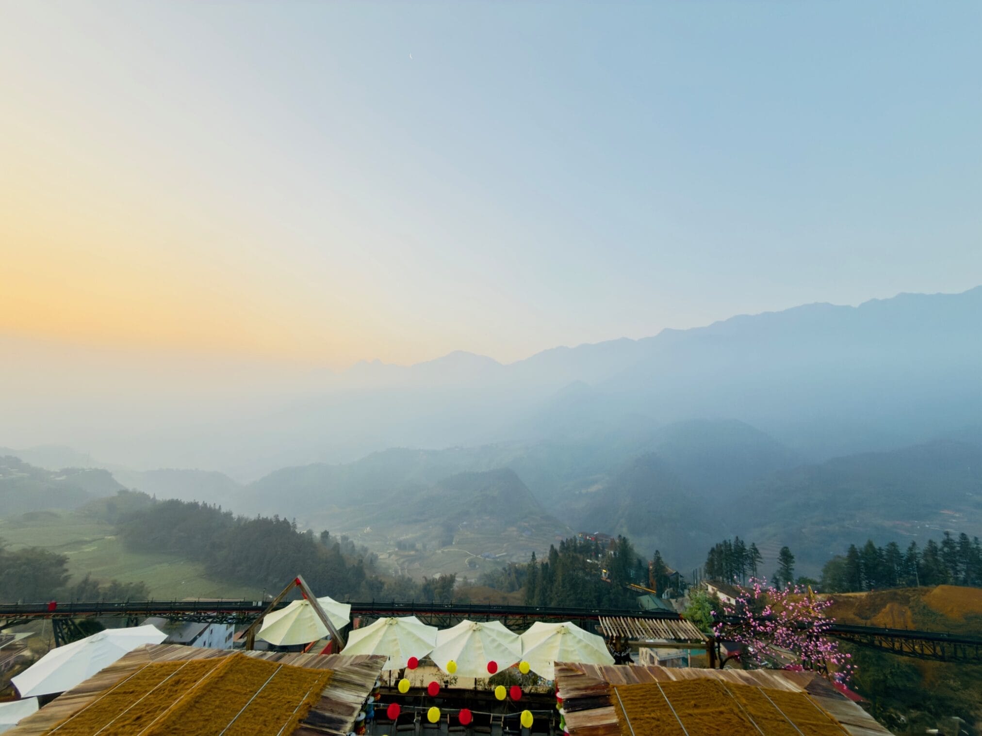 วิวทิวทัศน์ภูเขาในสายหมอกยามเช้า พร้อมหลังคาและเต็นท์สีขาว